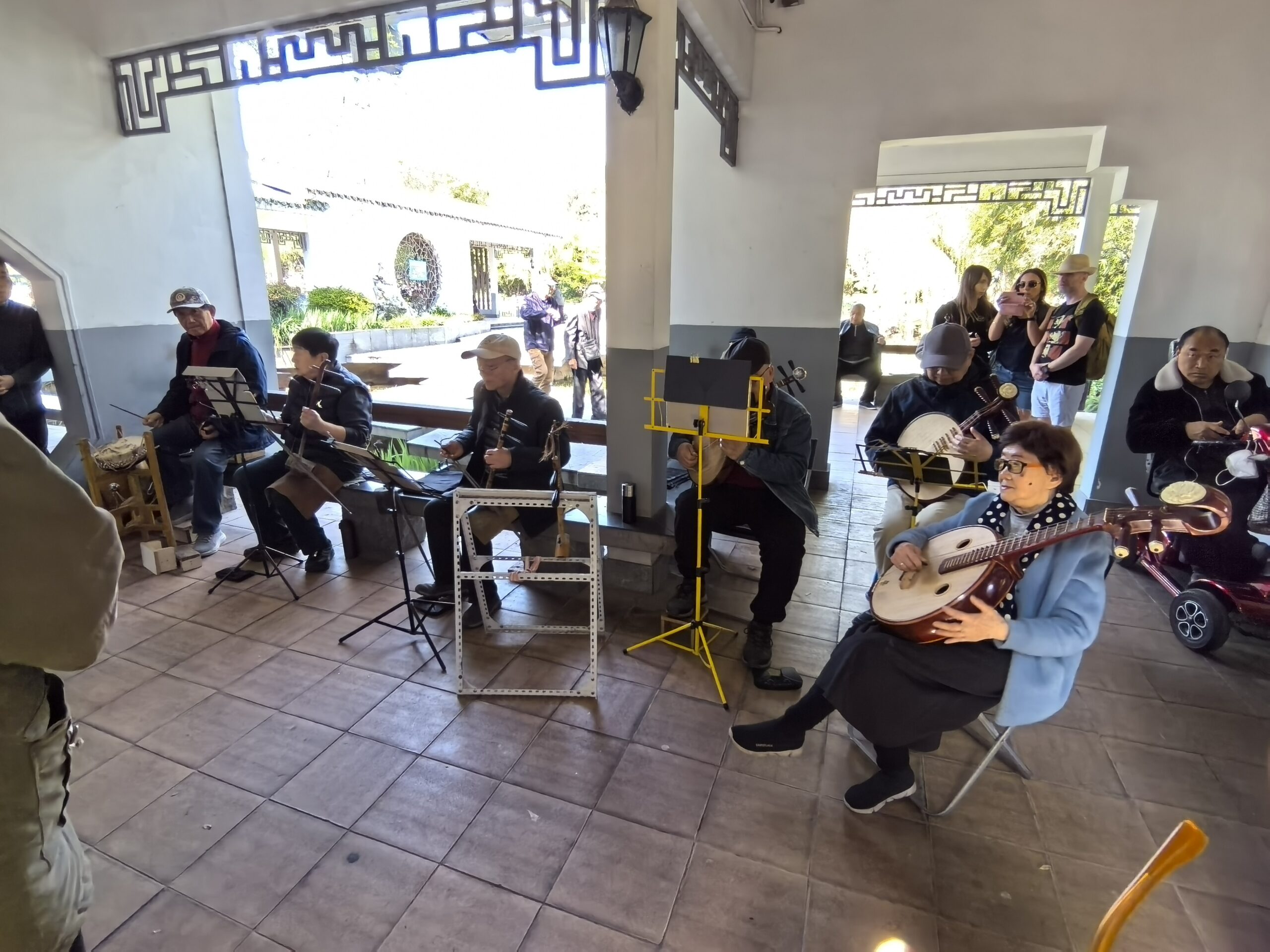 Musicians playing traditional instruments together in a Shanghai park pavilion