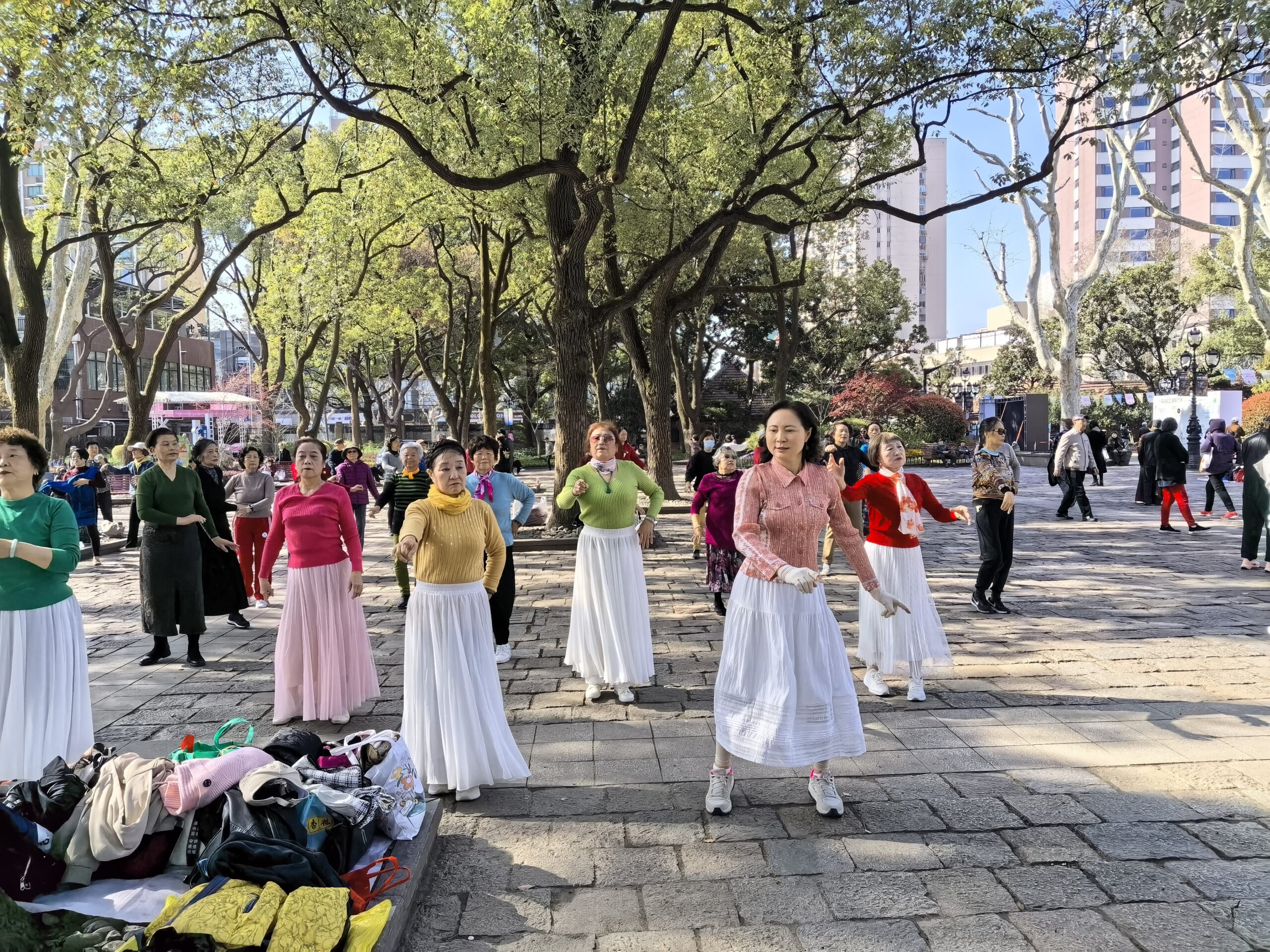 Women dancing together beneath the trees in a Shanghai park