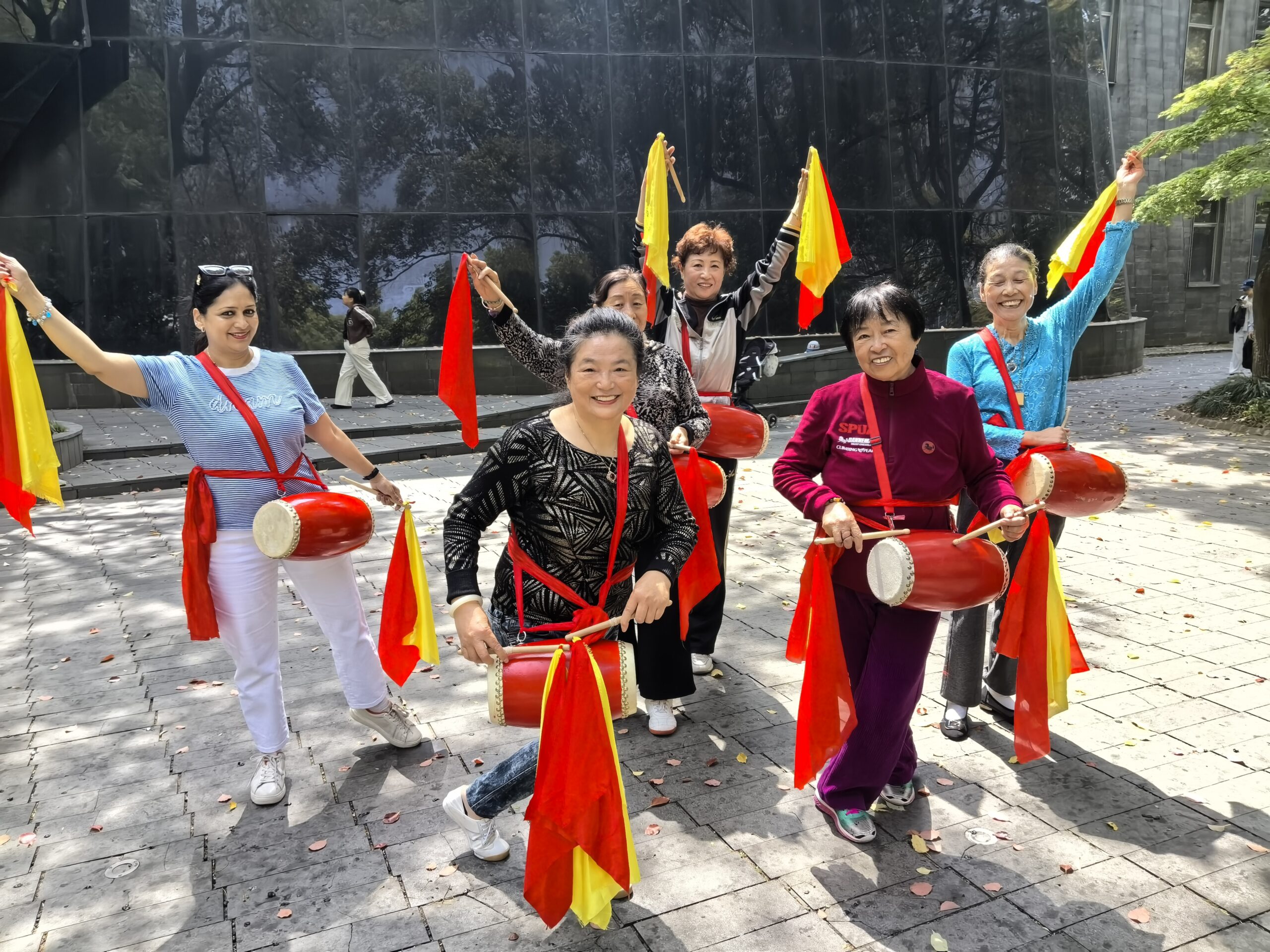 Women smiling with red waist drums and colourful ribbons in a Shanghai park
